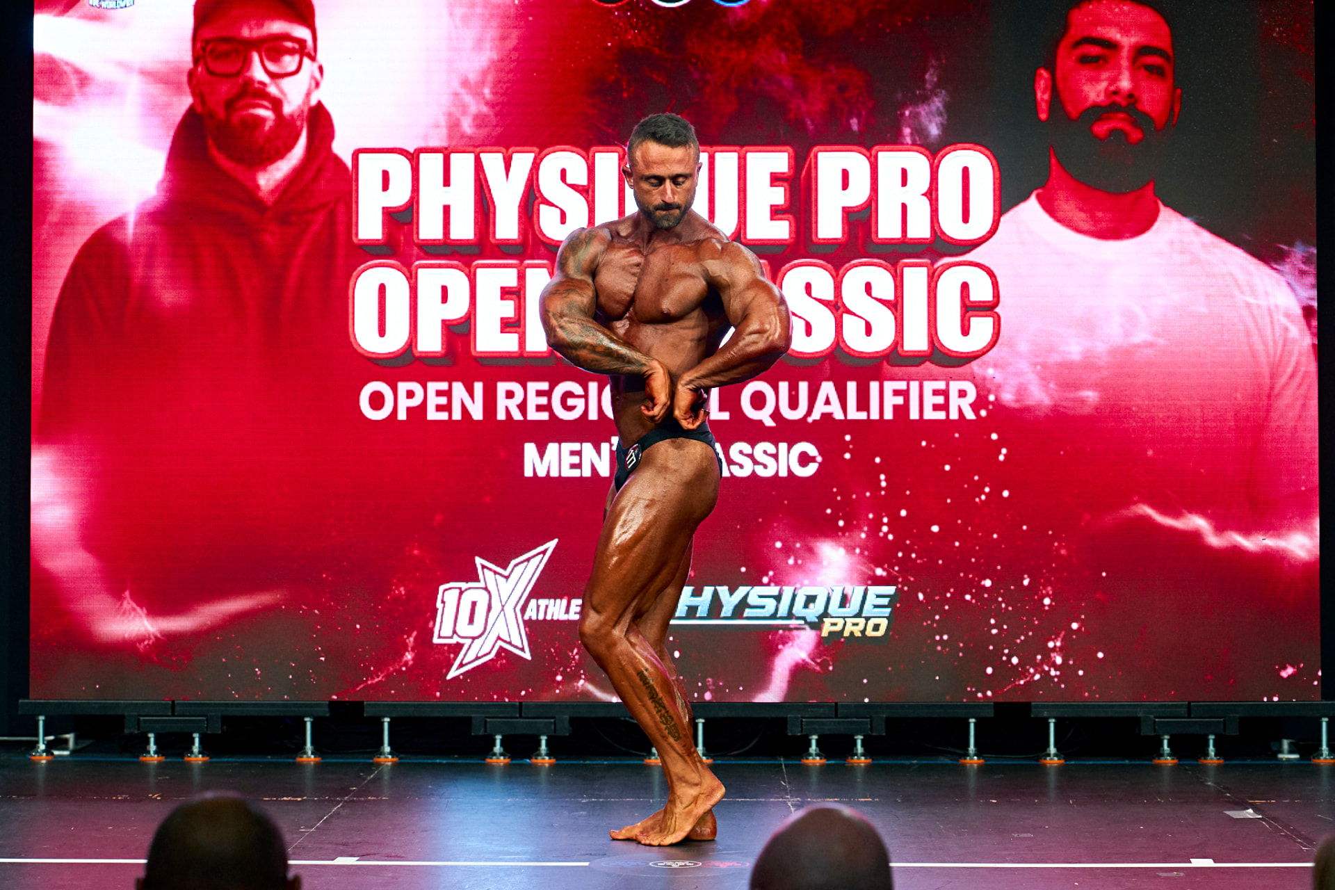 Josh King competing on stage at a bodybuilding show